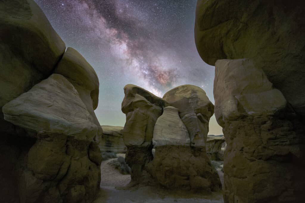 Mysterious rock hoodoos stand in clusters under the Milky Way.